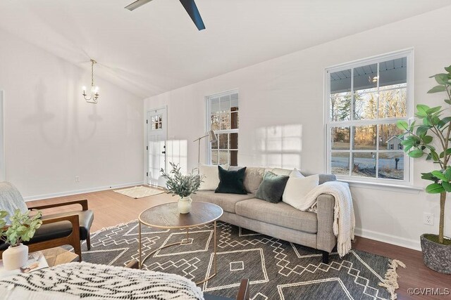 living room featuring ceiling fan with notable chandelier, vaulted ceiling, and dark hardwood / wood-style floors