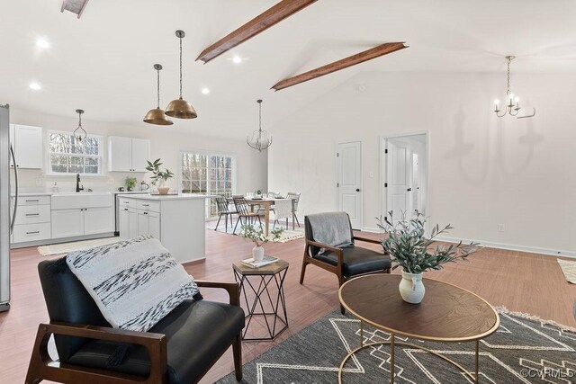 living room with sink, a chandelier, high vaulted ceiling, light wood-type flooring, and beam ceiling