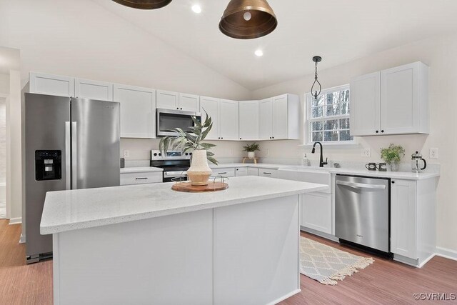 kitchen featuring a center island, hanging light fixtures, appliances with stainless steel finishes, light hardwood / wood-style floors, and white cabinets