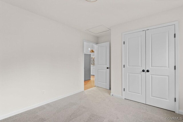 unfurnished bedroom with light colored carpet and a closet