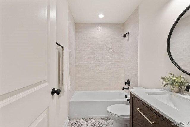 full bathroom featuring tiled shower / bath, vanity, and toilet