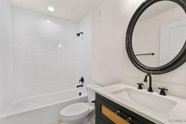 full bathroom featuring vanity, tiled shower / bath combo, and toilet