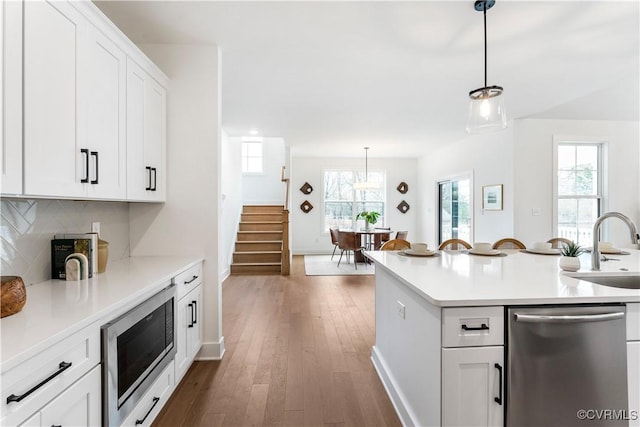 kitchen featuring pendant lighting, sink, white cabinets, dark hardwood / wood-style flooring, and stainless steel appliances