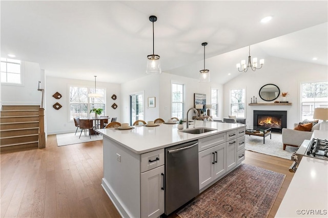 kitchen with sink, decorative light fixtures, stainless steel dishwasher, dark hardwood / wood-style floors, and an island with sink