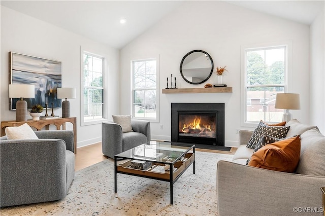 living room with vaulted ceiling, a healthy amount of sunlight, and light wood-type flooring