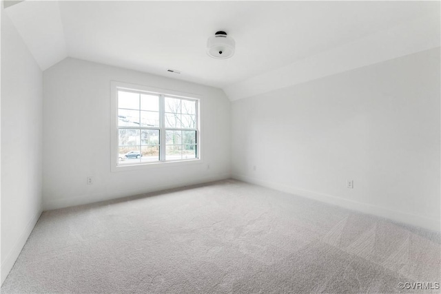 carpeted spare room with vaulted ceiling