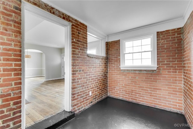 spare room featuring brick wall and concrete flooring