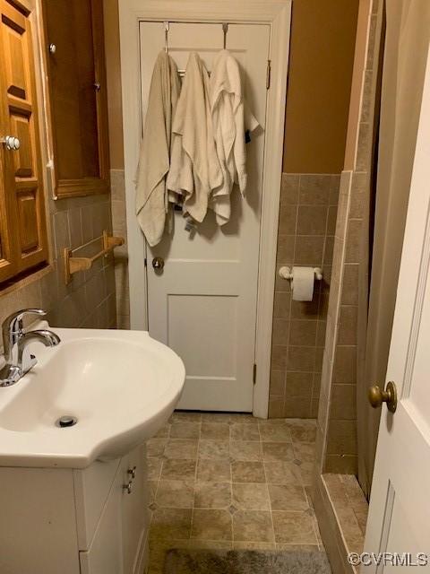 bathroom with vanity and tile walls