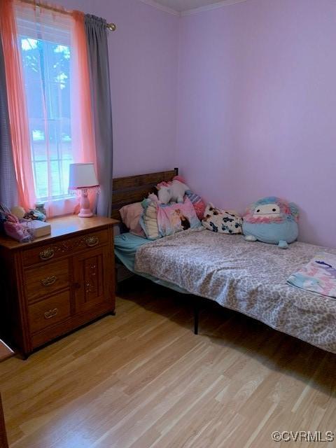 bedroom featuring ornamental molding and light hardwood / wood-style flooring