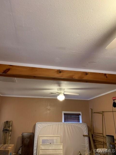 interior details featuring a textured ceiling, ornamental molding, and ceiling fan