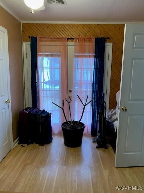 interior space with hardwood / wood-style flooring, ornamental molding, and wood walls