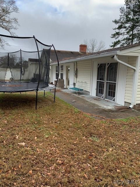 back of house with a lawn, a trampoline, and a patio area