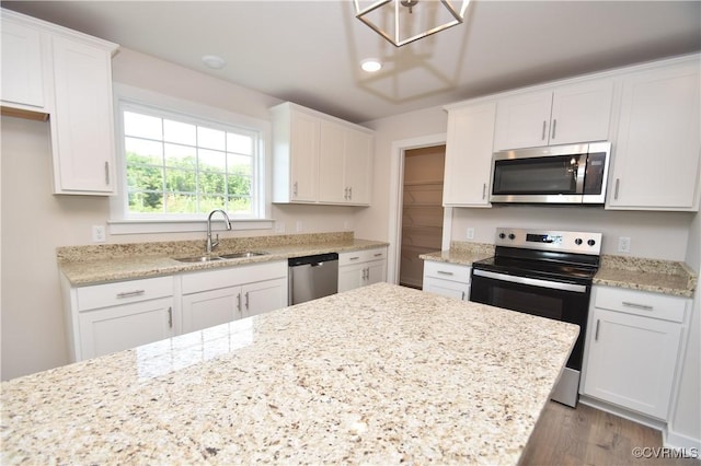 kitchen featuring white cabinetry, sink, light stone counters, and appliances with stainless steel finishes