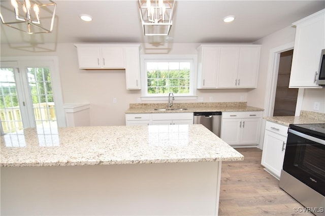 kitchen featuring sink, white cabinetry, light stone counters, hanging light fixtures, and stainless steel appliances