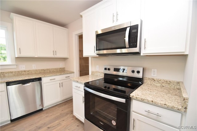 kitchen featuring appliances with stainless steel finishes, light stone countertops, light wood-type flooring, and white cabinets