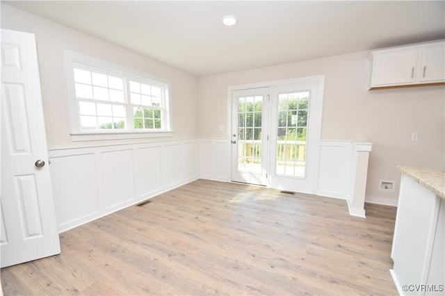 unfurnished dining area featuring a healthy amount of sunlight and light wood-type flooring