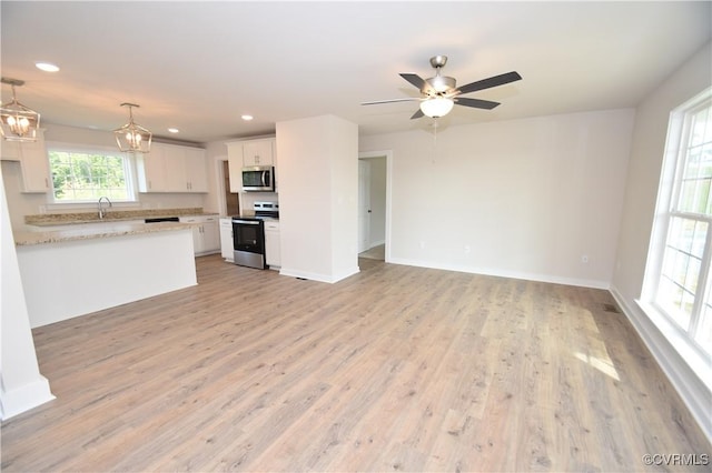 kitchen featuring sink, white cabinetry, decorative light fixtures, light hardwood / wood-style flooring, and stainless steel appliances