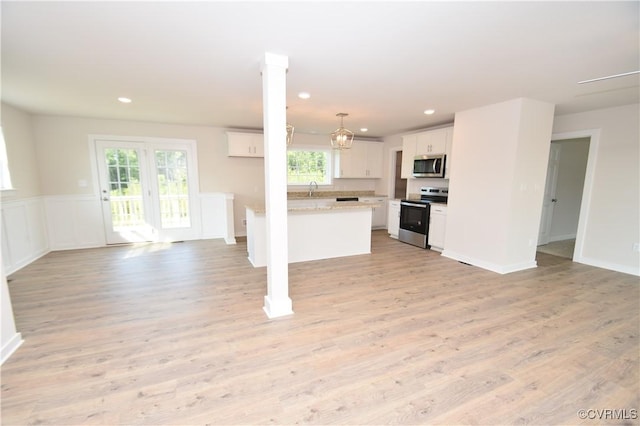 kitchen featuring white cabinetry, stainless steel appliances, light hardwood / wood-style flooring, and pendant lighting