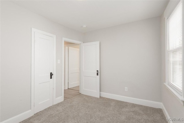 unfurnished bedroom with multiple windows and light colored carpet