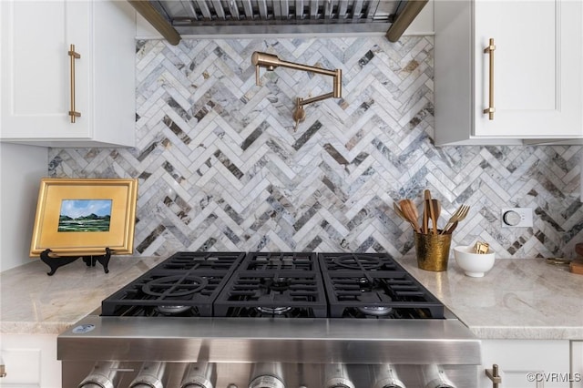 kitchen with white cabinetry, tasteful backsplash, light stone counters, and stove