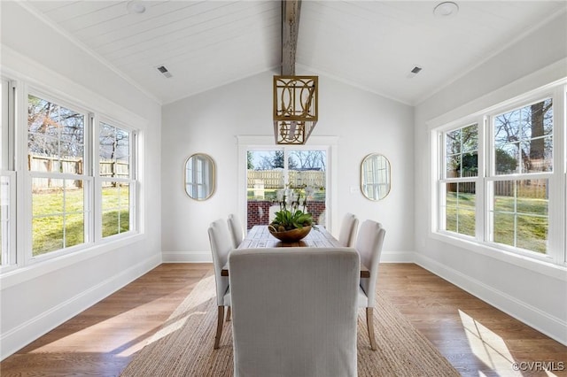 dining space featuring vaulted ceiling with beams and light hardwood / wood-style flooring