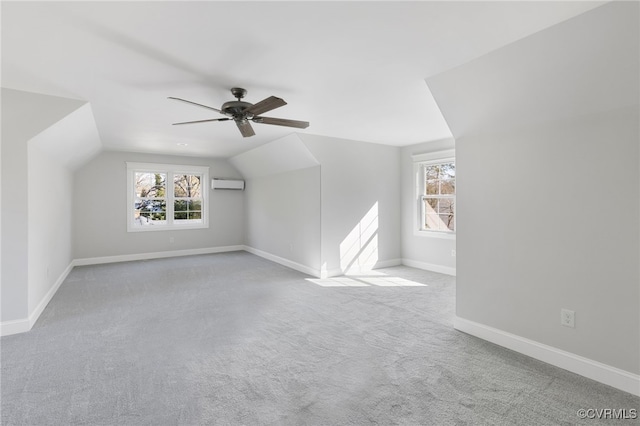 additional living space with light colored carpet, a wealth of natural light, a wall unit AC, and vaulted ceiling