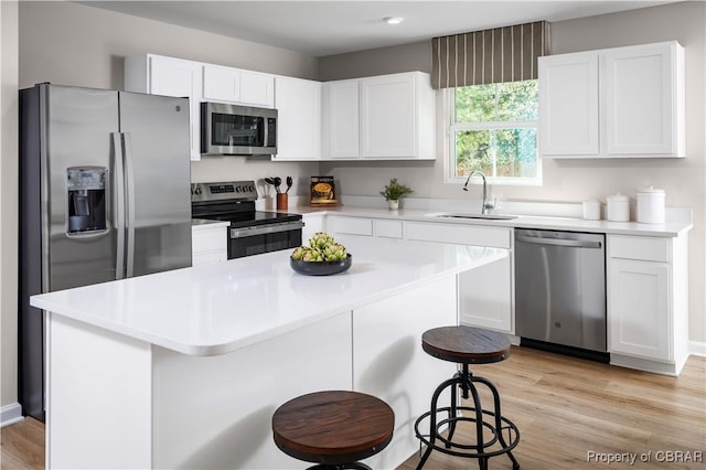 kitchen featuring a kitchen island, sink, a breakfast bar area, white cabinets, and stainless steel appliances