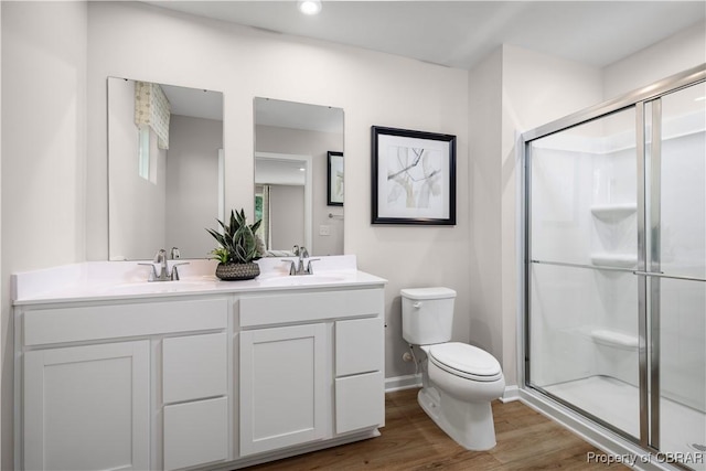 bathroom featuring toilet, hardwood / wood-style floors, vanity, and a shower with shower door