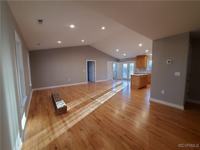 unfurnished living room with lofted ceiling, light hardwood / wood-style flooring, and french doors