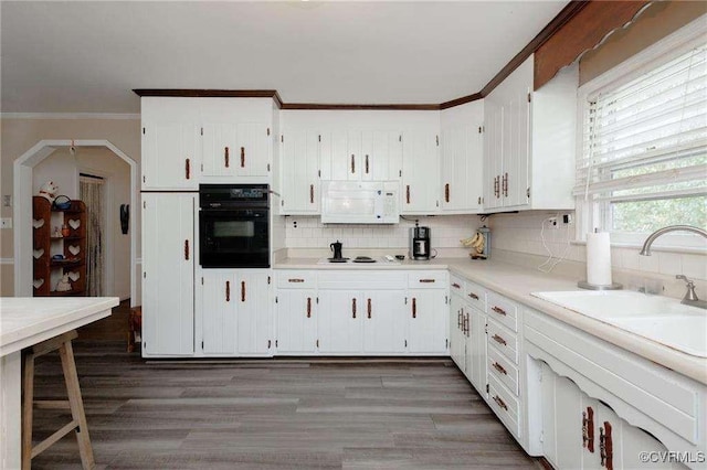 kitchen featuring sink, crown molding, tasteful backsplash, white appliances, and white cabinets