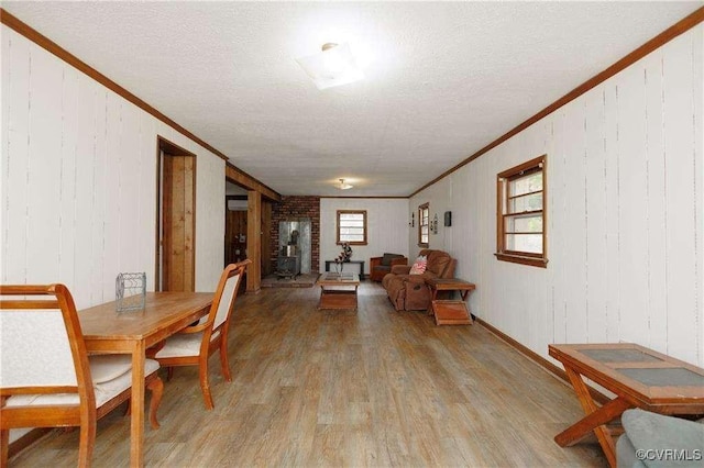 dining room featuring crown molding, light hardwood / wood-style flooring, and a textured ceiling