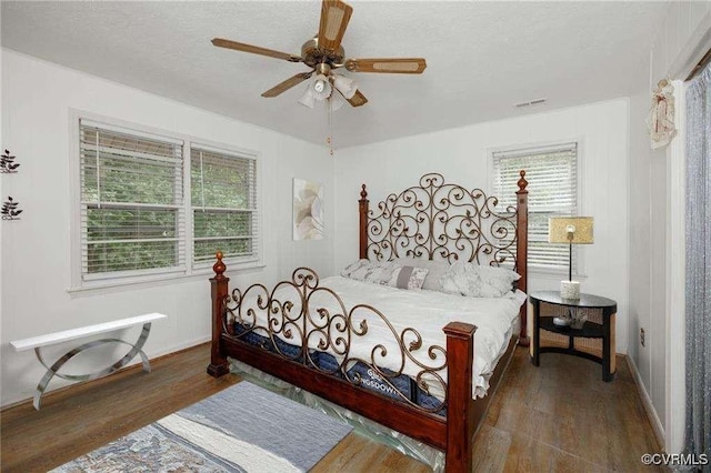 bedroom with ceiling fan, a textured ceiling, and dark hardwood / wood-style flooring