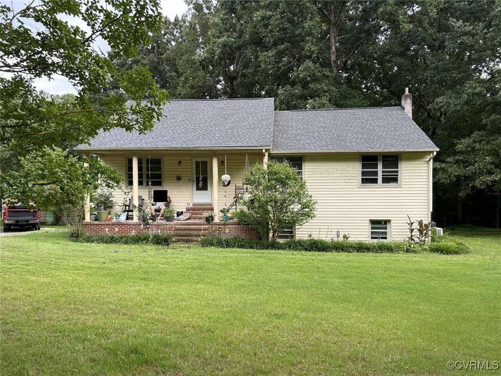 single story home featuring a porch, a front yard, a shingled roof, and a chimney