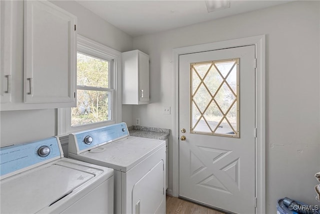 laundry area with cabinets, light hardwood / wood-style flooring, and washing machine and clothes dryer