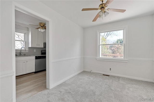 carpeted empty room featuring ceiling fan and sink