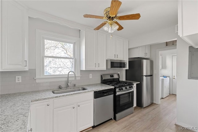 kitchen featuring sink, appliances with stainless steel finishes, backsplash, light stone countertops, and white cabinets