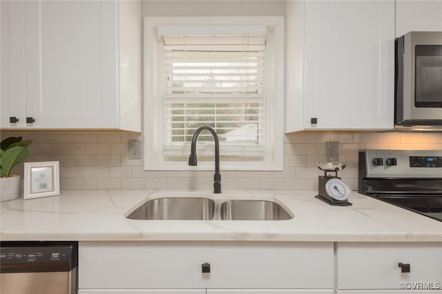 kitchen with light stone countertops, white cabinetry, and appliances with stainless steel finishes