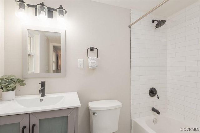 full bathroom featuring tiled shower / bath, vanity, and toilet