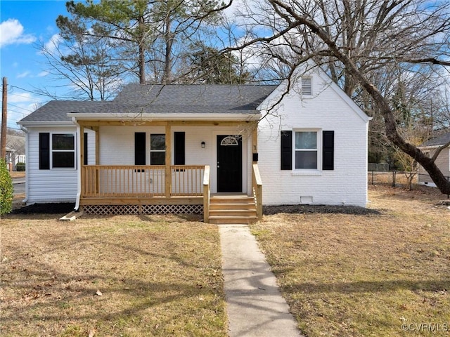 bungalow-style house with brick siding, roof with shingles, a porch, fence, and a front lawn