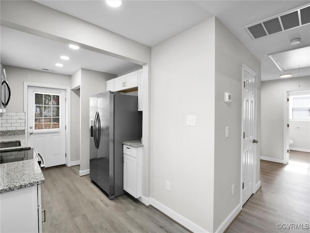 kitchen with white cabinetry, tasteful backsplash, stainless steel fridge with ice dispenser, light stone countertops, and light hardwood / wood-style floors