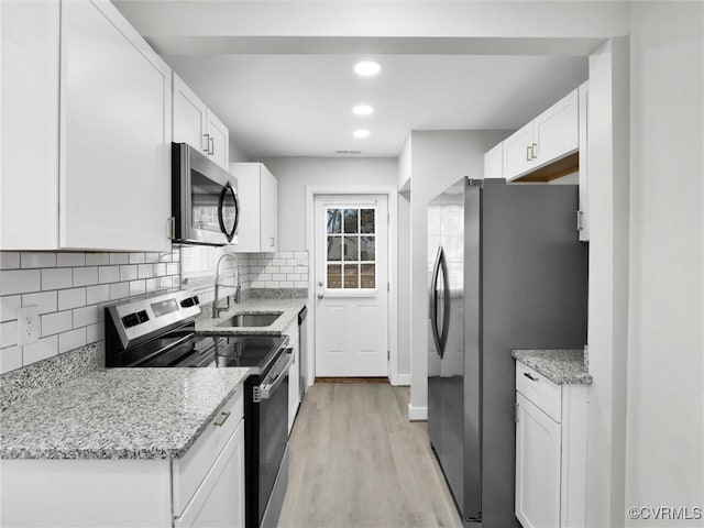 kitchen with sink, stainless steel appliances, white cabinets, and light stone countertops