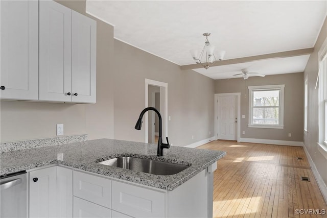 kitchen with white cabinetry, sink, stainless steel dishwasher, and light stone countertops