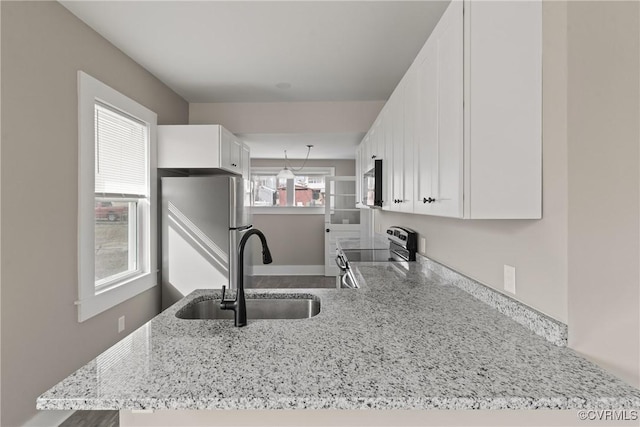 kitchen featuring sink, white cabinetry, stainless steel appliances, light stone countertops, and kitchen peninsula