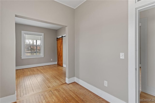 empty room with wood-type flooring and a barn door