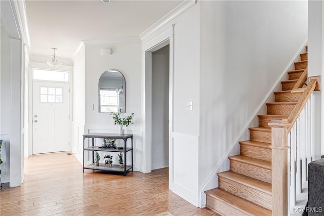 foyer with crown molding and light hardwood / wood-style flooring