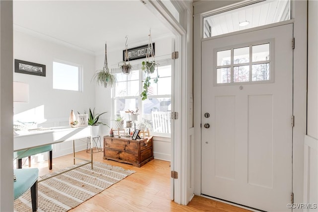 doorway with ornamental molding and light wood-type flooring