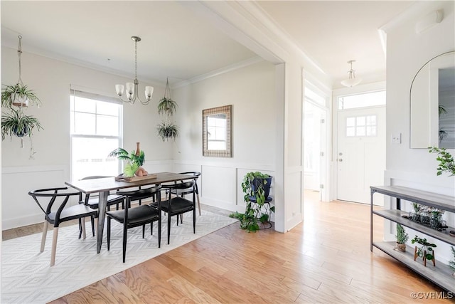 dining room with an inviting chandelier, ornamental molding, and light hardwood / wood-style flooring