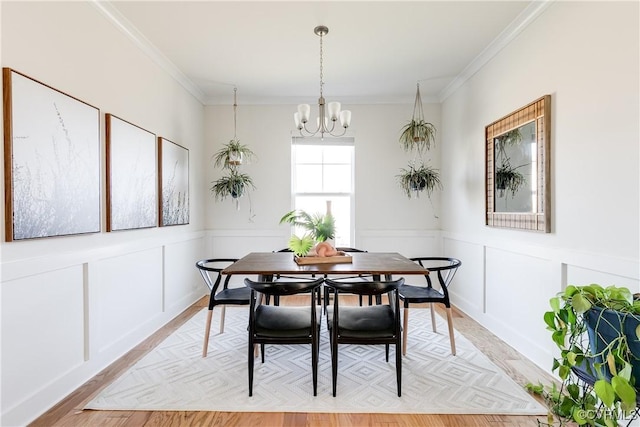 dining area featuring an inviting chandelier, ornamental molding, and light hardwood / wood-style flooring