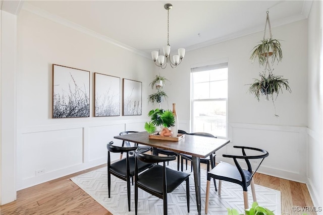 dining area with ornamental molding, a notable chandelier, and light hardwood / wood-style floors