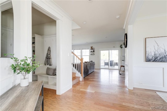 hallway with light hardwood / wood-style flooring and ornamental molding